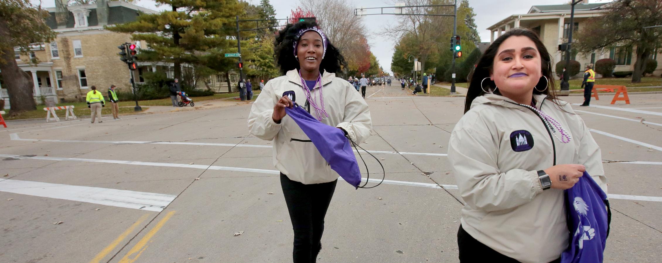 Two students participate in community events as they walk down the street.