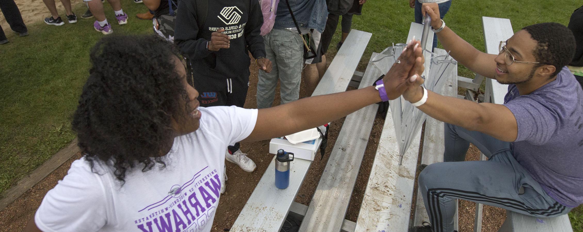 Two students high five.