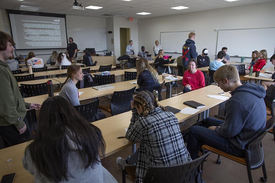 Students is at rowed tables in a classroom.